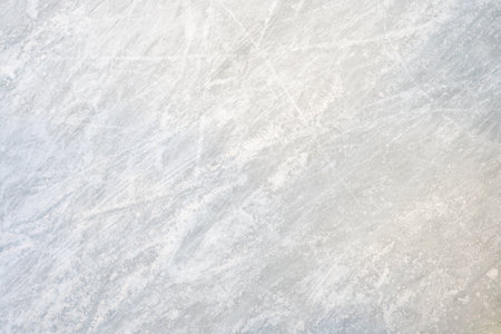 Icy background on rink reveals visible traces of skating, capturing the essence of winter sport. Texture of ice on skating rink is apparent from a top view, showcasing sheet of scratched ice.の写真素材