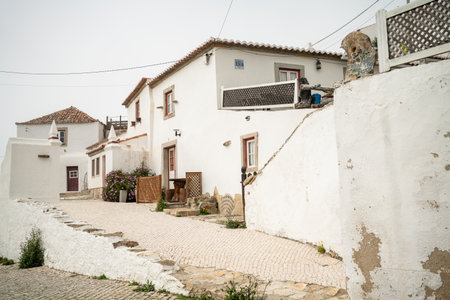 Exterior of beautiful white two-story houses in town. Typical empty street along white buildings in city. Residential buildings in Portugal city under clear sky.の写真素材