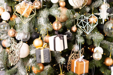 Christmas present gift box stacked close up. Holiday sale concept. Many gift box black, white, orange color with gold ribbon and light garlandの写真素材