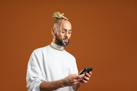 Confident black gay man with bright makeup standing isolated on brown background, dressed white. Exudes sense of pride and individuality. Diversity power of personal style. Side viewの写真素材