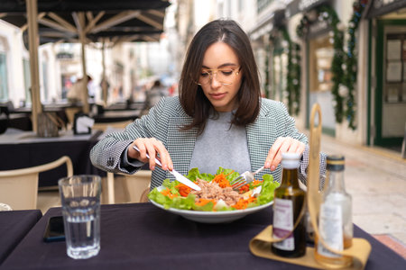 Stylish business woman eating healthy salad on restaurant terrace, feeling happy on summer dayの写真素材