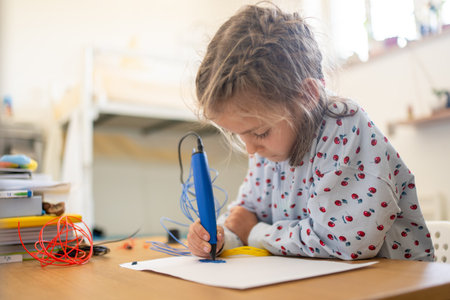 3D pen cute girl creating plastic 3D model, drawing. Smart child drawing with pen on paper at table. Technology. Robotics. STEAM education. Modern technologies.の写真素材