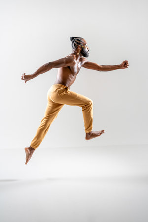 Shirtless African American gay man running isolated on white background. Full length side view of athletic man jogging in white studio. Equality concept.の写真素材