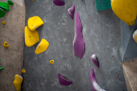 Closeup of climbing holds on gray wall in gym. Full frame of artificial rock-climbing wall with colorful handles.の写真素材