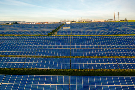 Drone view of blue solar panels on agricultural field during sunny day. The landscape is fully...