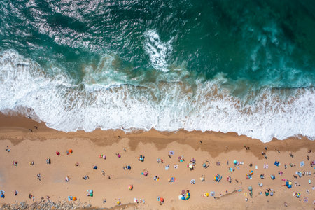 Overhead drone shot of anonymous tourist and parasols on sandy seashore. Directly above view of...