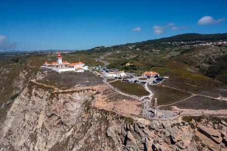 Stunning drone view captures iconic Cabo da Roca lighthouse perched on towering cliffs in Portugal, overlooking vast rugged landscapes at the westernmost point of mainland Europeの写真素材