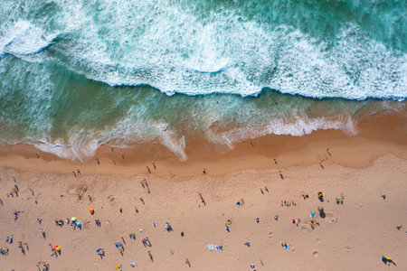 Overhead drone shot of unreognizable tourists and parasols on sandy seashore. Directly above view of people enjoying summer vacations at beach during sunny dayの写真素材