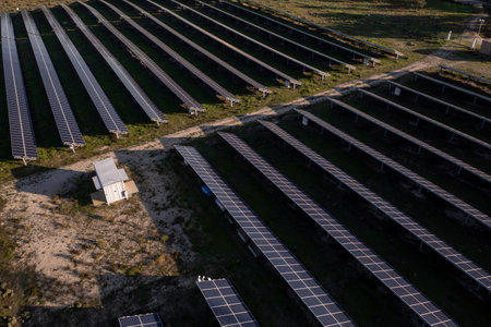 High-angle view of rows of solar panels in countryside fields on sunny day, harnessing clean energy and reflecting sustainable agricultural practices in serene, open landscapeの写真素材
