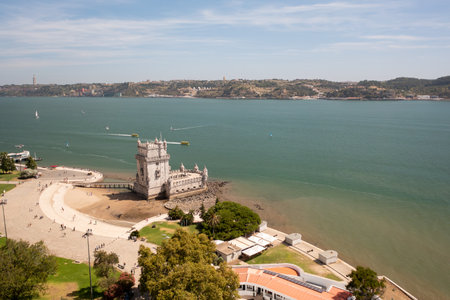 Aerial drone shot of Belem Tower, a historic fortress on the Tagus River in Lisbon, with tourists visiting and exploring the iconic monumentの写真素材