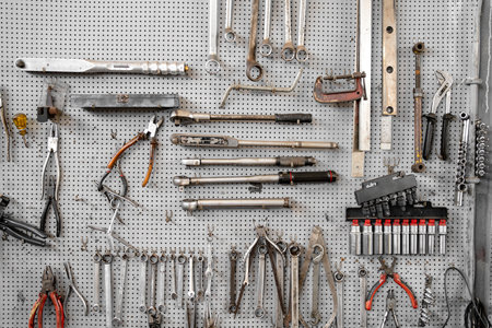 Various wrenches and hand tools hanging on pegboard in workshop. Neatly organized tools include combination wrenches, pliers, and adjustable wrenches for mechanical workの写真素材