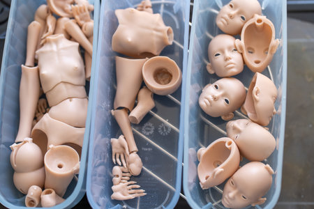 Closeup of silicone doll parts in containers, including various body and face pieces. Parts are awaiting assembly in the doll-making processの写真素材