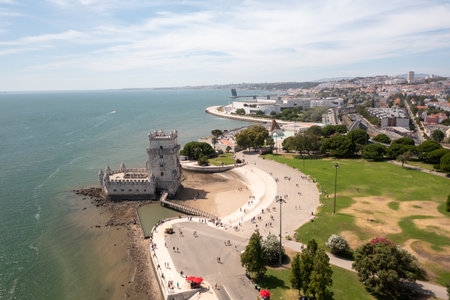 Aerial drone shot of Belem Tower historic fortress on Tagus River in Lisbon, with tourists visiting and exploring the iconic monumentの写真素材