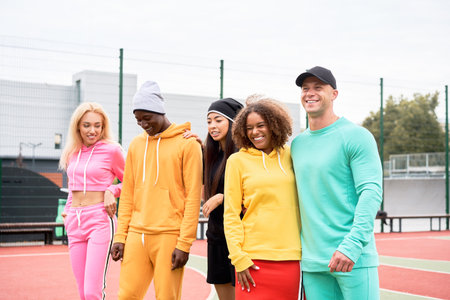 Multi-ethnic group teenage friends. African-american asian caucasian student spending time together Multiracial friendship Happy smiling People dressed colorful sportswear meeting outdoor sportgroundの写真素材
