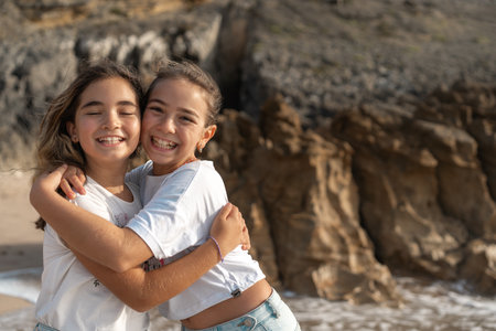 Happy girls hugging each other on beach near sea smiling and enjoying fun summer vacation together...