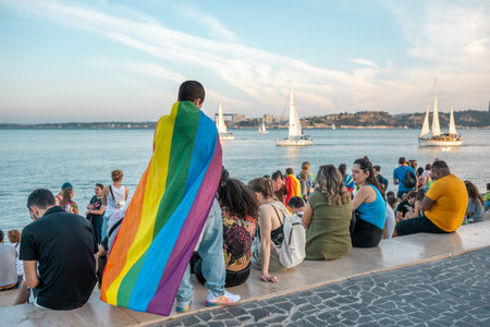 Lisbon, Portugal 17 June 2023 Crowds gather by the waterfront for an LGBT pride celebration as a person in a rainbow cape stands out.のeditorial素材
