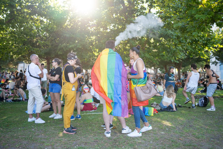 Lisbon, Portugal 17 June 2023 Participants gather in a vibrant park, celebrating LGBT pride with colorful outfits and flags. The festive atmosphere is enhanced by music and laughter under bright sun.のeditorial素材