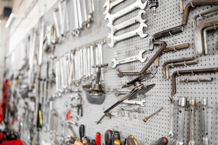 Various hand tools neatly arranged on perforated wall inside workshop. Organized work environment...
