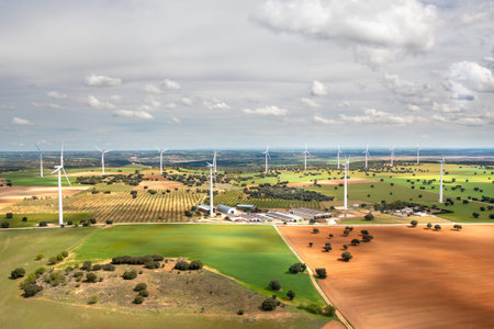 Aerial drone view of wind turbines installed across agricultural fields. Renewable energy production...