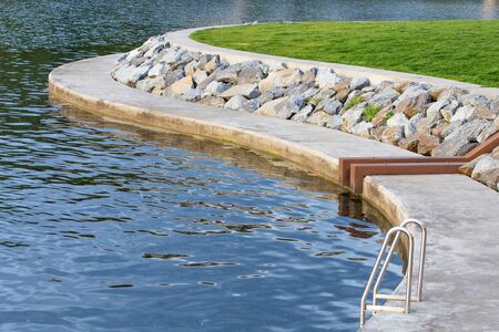Silver Pool Ladder With An Oval Rock Formation and Green Grassの写真素材
