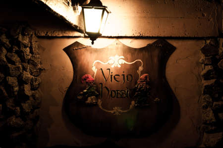 Logo shield with gnomes iluminated by old lamp. Translation old hobbit in spanishの写真素材