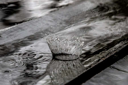Rain drop splash in wooden floor bouncing and shaping water crown