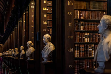 DUBLIN, IRELAND, DECEMBER 21, 2018: The Long Room in the Trinity College Library, home to The Book of Kells. Perspective view of the place, with large quantity of books and chest statuesのeditorial素材