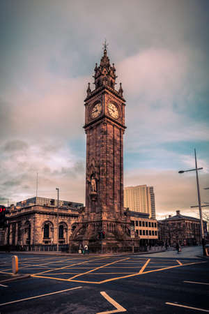 BELFAST, NORTHERN IRELAND, DECEMBER 19, 2018: People passing by Queen's Square where Albert Memorial Clock Tower is situated. Completed in 1869 and is one of the best known landmarks of Belfastのeditorial素材