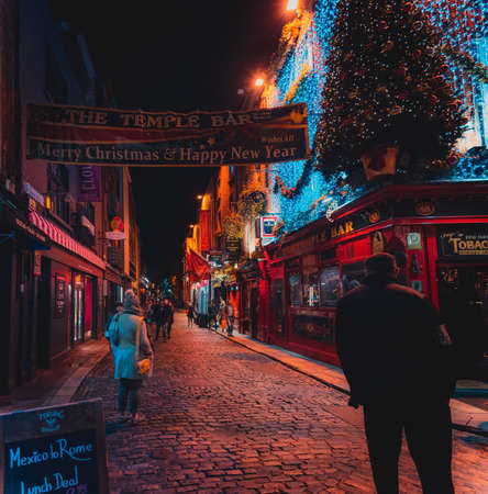 DUBLIN, IRELAND, DECEMBER 24, 2018: People walking in Temple Bar historic district,a cultural quarter with lively nightlife. Nightscene of the bar, full of lights and its typically irish pub look.のeditorial素材