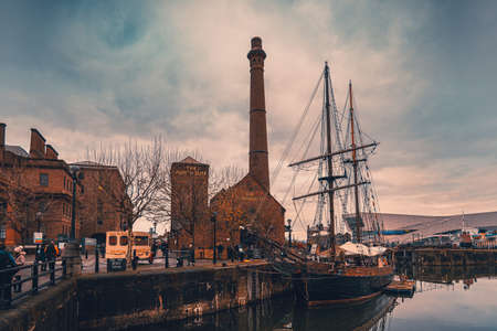 LIVERPOOL, ENGLAND, DECEMBER 27, 2018: People walking along Albert Docks with a frigate floating in the river at one side and the former pumphouse, built in 1870 and restored as a British pubのeditorial素材