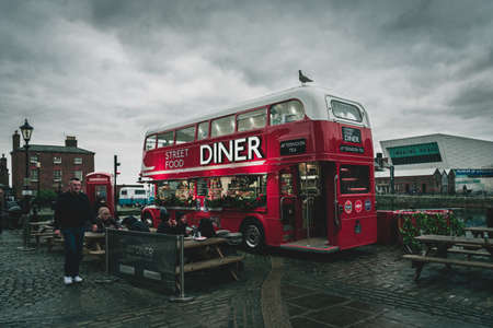 LIVERPOOL, ENGLAND, DECEMBER 27, 2018: People enjoying a meal on a cloudy day, beside a red double decker bus as food truck, decorated for christmas timeのeditorial素材