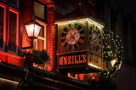 DUBLIN, IRELAND, DECEMBER 24, 2018: View of the clock on the exterior of the O'Neill's Pub and Kitchen on Suffolk Street, dimly lit and decorated for christmas timeのeditorial素材