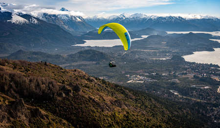 Paragliding over Nahuel Huapi lake and mountains of Bariloche in Argentina, with snowed peaks in the background. Concept of freedom, adventure, flying.のeditorial素材