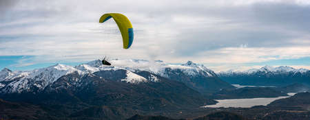Panoramic view of paragliding over Nahuel Huapi lake and mountains of Bariloche in Argentina, with snowed peaks in the background. Concept of freedom, adventure, flying.のeditorial素材