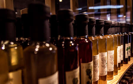BARILOCHE, ARGENTINA, JUNE 19, 2019: Perspective view of bokeh of liquor bottles in a shop over shelves. Translation of flowers in Spanishのeditorial素材