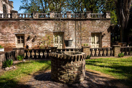 GONZALEZ CATAN,ARGENTINA,SEPTEMBER 28,2019: Old water well made of bricks and cobblestone surrounded by an abandoned house.のeditorial素材
