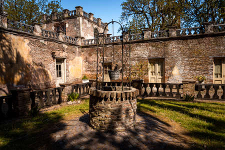 GONZALEZ CATAN,ARGENTINA,SEPTEMBER 28,2019: Old water well made of bricks and cobblestone surrounded by an abandoned house.のeditorial素材