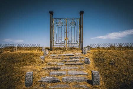 Old rusty iron gate in the middle of a field leading to nowhere. Concept of purgatory, limits, frontiers and freedom.の写真素材