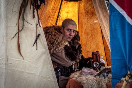 A shaved woman cosplaying a Nordic rune reader in a medieval fair.