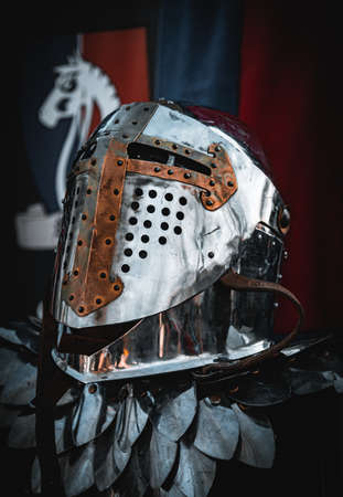 Shiny silver medieval iron knight helmet with a golden cross, full of scratches due to battles.のeditorial素材