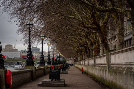 LONDON, ENGLAND, DECEMBER 29, 2018: Perspective view of the riverside of Thames in London, with street lamps and trees decorated with Christmas lights while people walk alongのeditorial素材