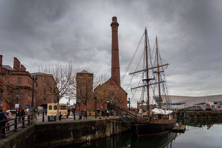 LIVERPOOL, ENGLAND, DECEMBER 27, 2018: People walking along Albert Docks with a frigate floating in the river at one side and the former pumphouse, built in 1870 and restored as a British pub.のeditorial素材