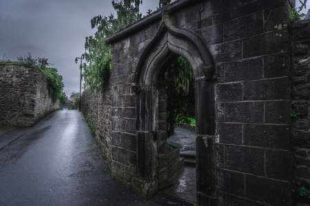 KILKENNY, IRELAND, DECEMBER 23, 2018: Spooky old stone and very wet entrance gate of a graveyard with mold and lichen growing. Concept of desolation and damageのeditorial素材
