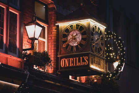 DUBLIN, IRELAND, DECEMBER 24, 2018: View of the clock on the exterior of the O'Neill's Pub and Kitchen on Suffolk Street, dimly lit and decorated for christmas timeのeditorial素材