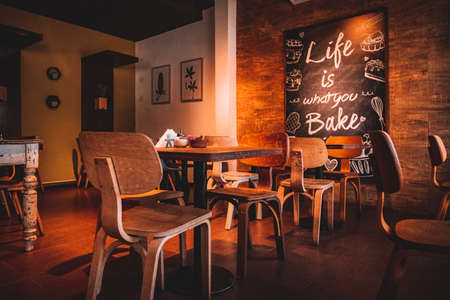 Interior of a beautiful and cozy cafe, with empty chairs and a nice quote in a wall.のeditorial素材