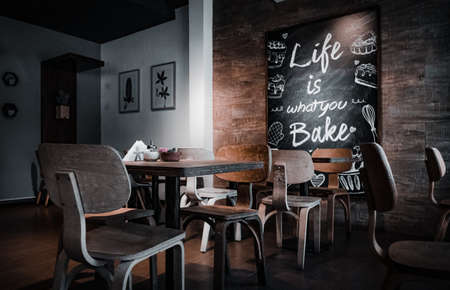 Interior of a beautiful and cozy cafe, with empty chairs and a nice quote in a wall.のeditorial素材