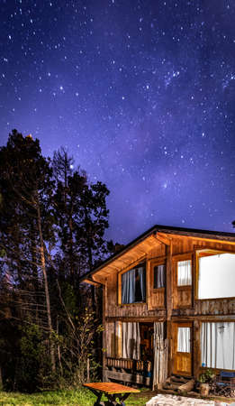 BARILOCHE, ARGENTINA, JUNE 19, 2019: Exterior of a wooden cozy and relaxing cabin in the forest with an amazing starred sky.のeditorial素材