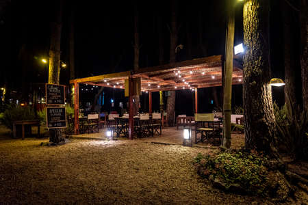 Night scene of an elegant outdoor bar illuminated by small hanging bulbsの写真素材