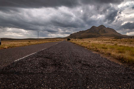 The old Golds Road at highest point in San Luis, Argentina, which climbs steppe mountains while a heavy storm is comingの写真素材