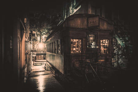Very old wooden wagon with used books for sale inside, used as books shop, at night, dimly illuminated from behindの写真素材